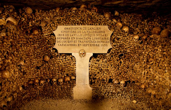 Piles of human bones and a signpost in French in the Parisian catacombs