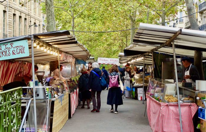 People shop at a covered outdoor market in Paris