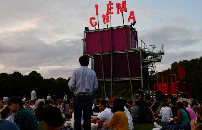 People sitting on blankets, waiting to watch a show at a Paris outdoor cinema