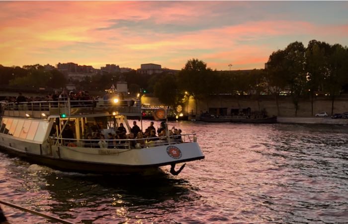 A tour boat cruising down the Seine river at sunset