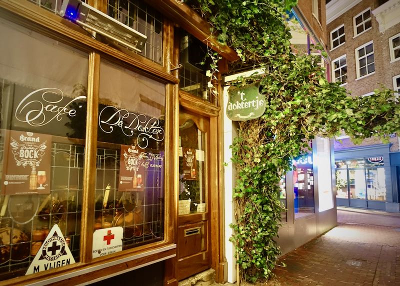 Exterior windows of a ivy-clad bar on a small Amsterdam pedestrian lane