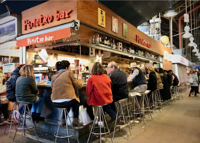 Patrons eat around a tapas stand inside a food market