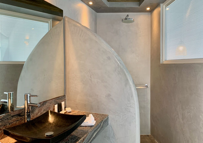 Bathroom with marble walls and a volcanic rock bowl sink.