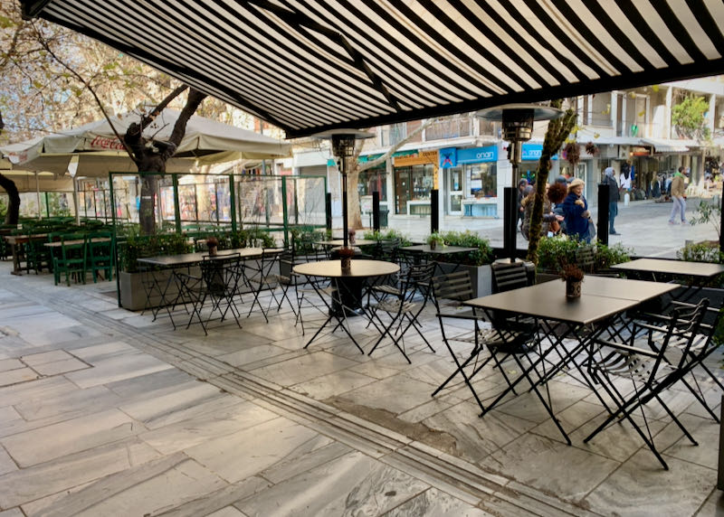Restaurant canopy with empty tables on a pedestrian plaza.