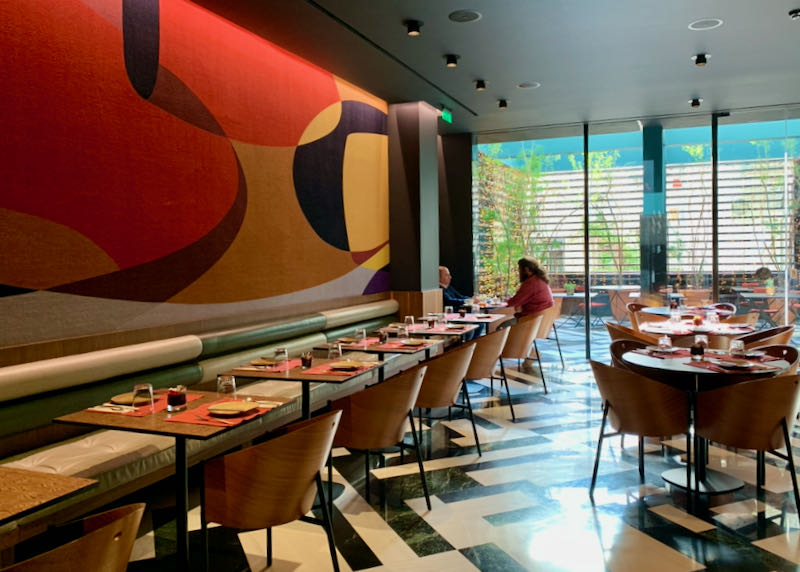Empty restaurant with a large colorful mural and black and white marble tiled floor