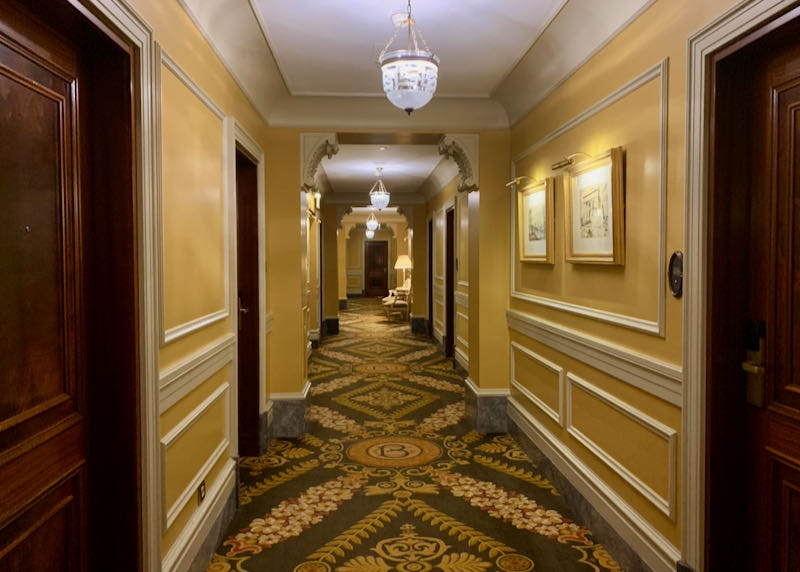 Ornate hotel hallway with plush carpeting and chandeliers