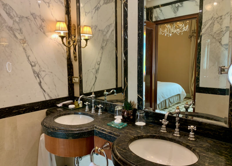 Double basin sinks in a marble-clad hotel bathroom.