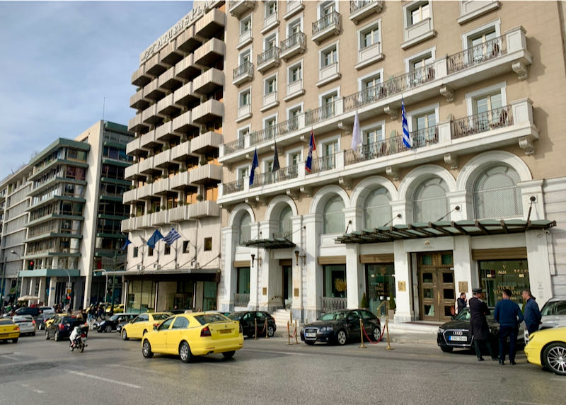 Exterior street view of the King George Hotel in Athens, with taxis parked in front