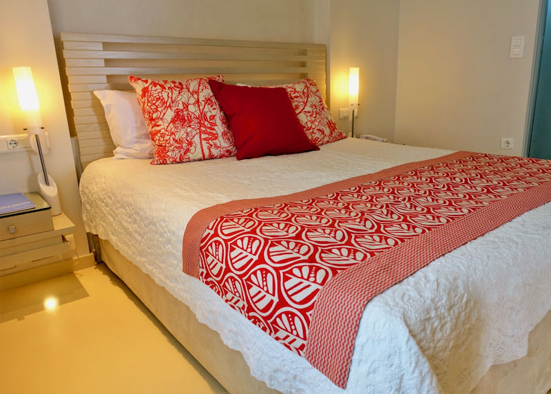 Wooden bed with white quilt and red patterned coverlet