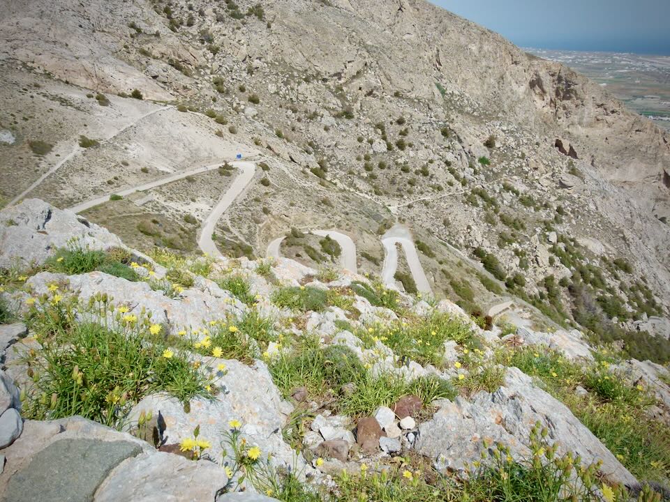 Overhead view of a switchback road leading up a low mountain.