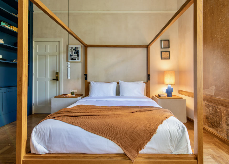 Hotel room with a modern four-poster bed and a wall of bookshelves