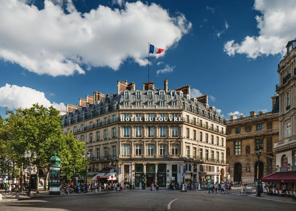 Exterior of a paris hotel with classic Haussmann roof and a French flag flying