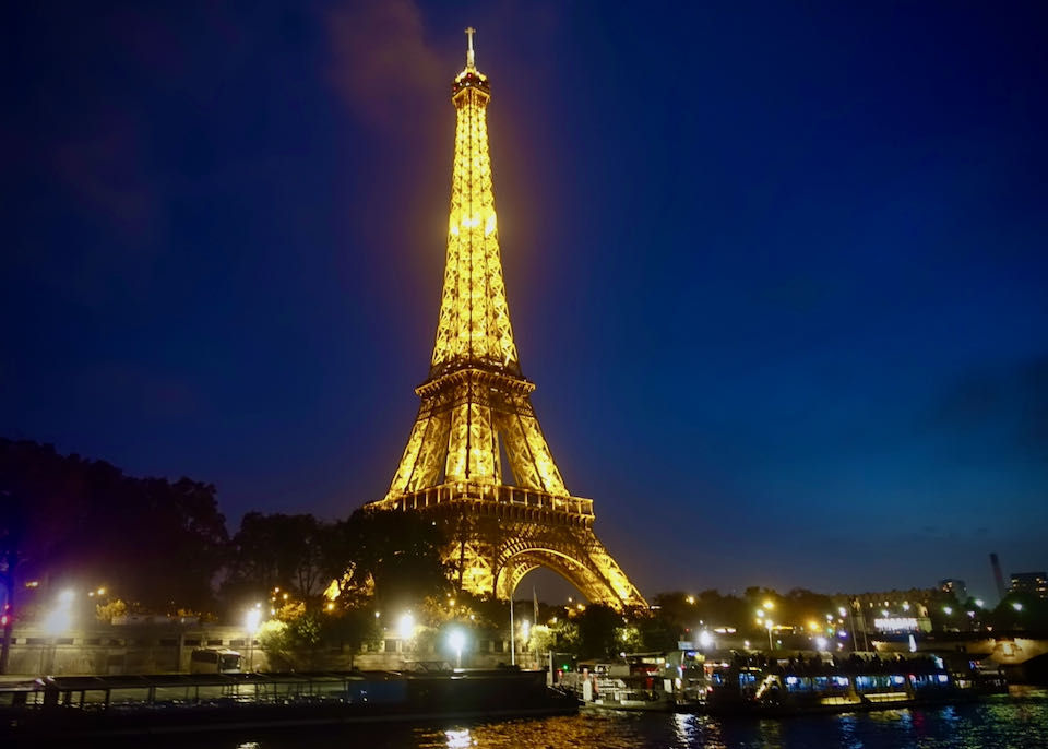 The Eiffel Tower lit up at night, as seen from a boat on the Seine