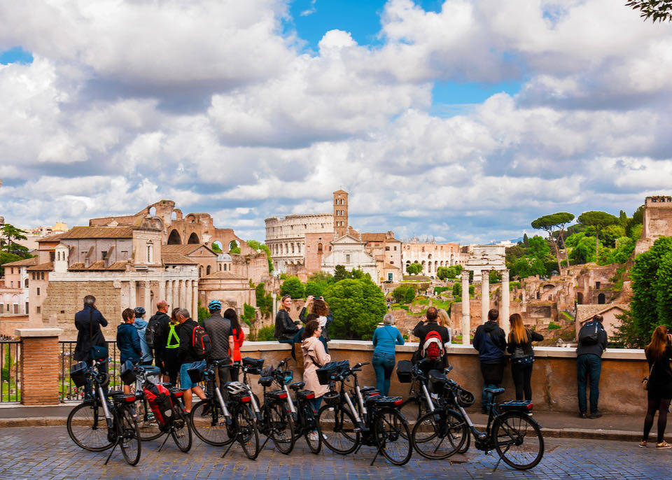 Tourists on a bike tour overlook Rome's historic center with Roman Forum ancient ruins