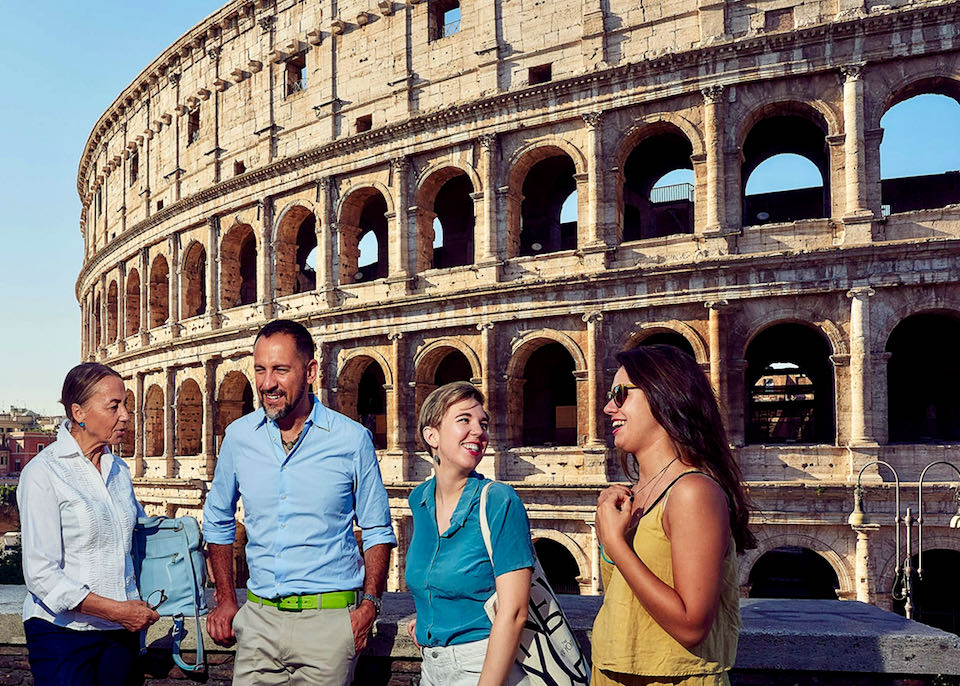 A female tour guide talks to a group of tourists in front of the Colosseum in Rome