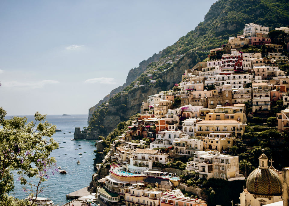 Colorful houses and buildings terraced up the steep cliffs of the Amalfi coastline.