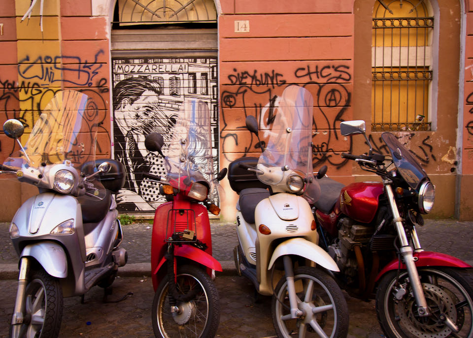 Motorbikes parked near a colorful wall adorned with graffiti in the bohemian-artsy neighborhood of San Lorenzo.
