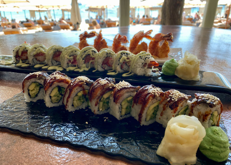 Two trays of sushi on a beachfront dining table