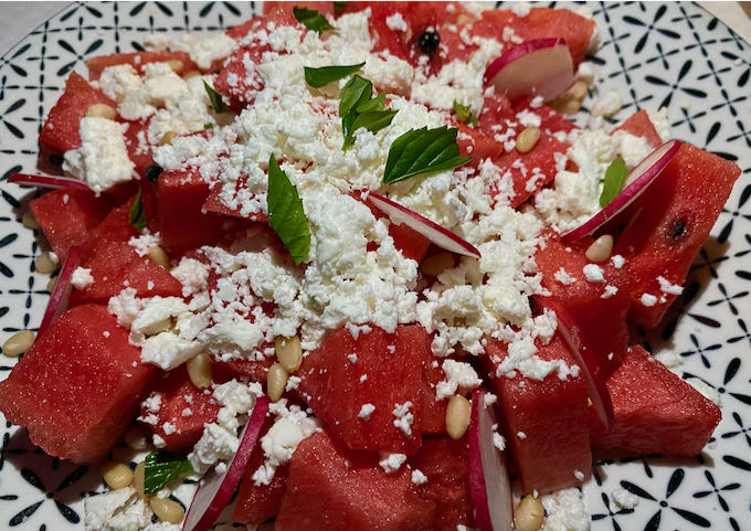 Watermelon salad with radish, feta cheese, pine nuts, and mint leaves.