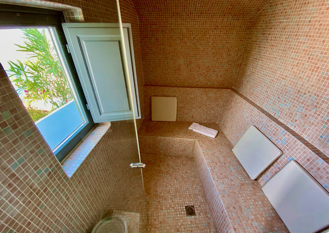 Coral-tiled steam room with a window overlooking the sea