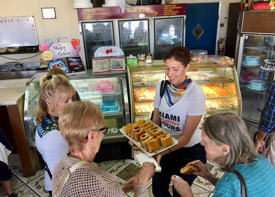 A guide serves Cuban pastries to a group of travelers in a Little Havana bakery.