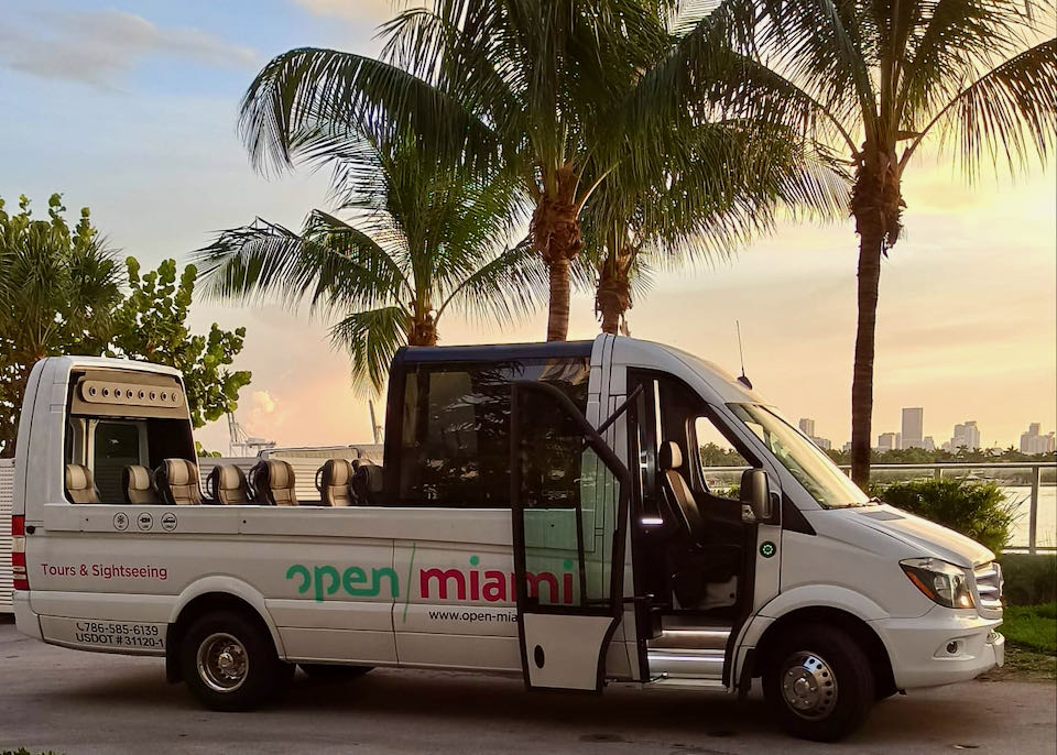 An open-top bus sits empty near a beach in Miami