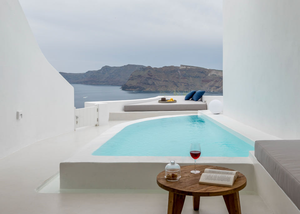 Private plunge pool on a hotel terrace with built-in lounge chair and caldera views
