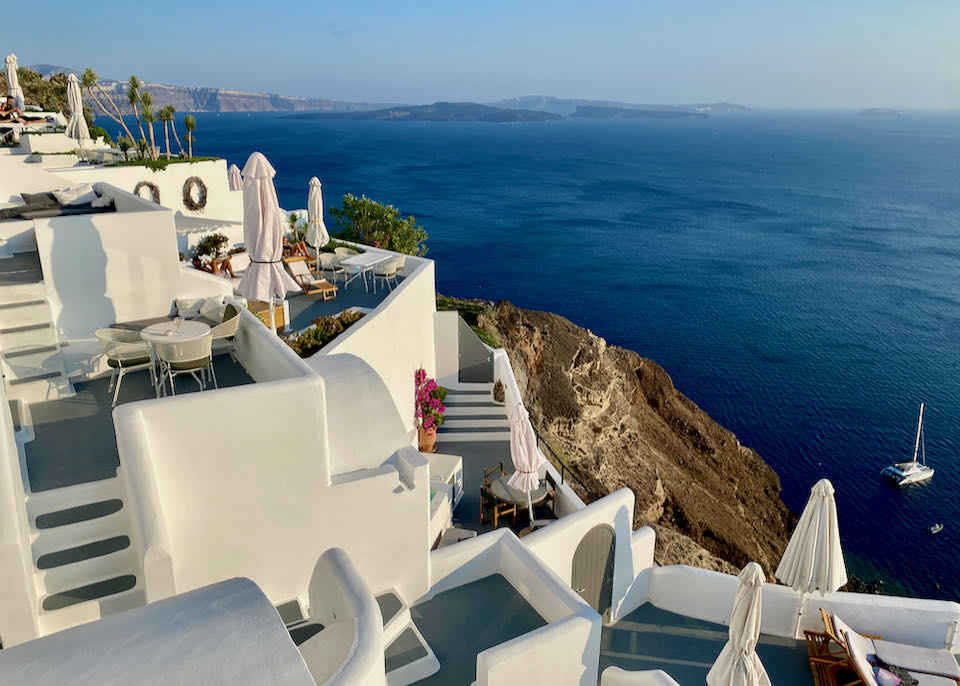 White staircases spill down the cliffside past hotel terraces in Oia, Santorini