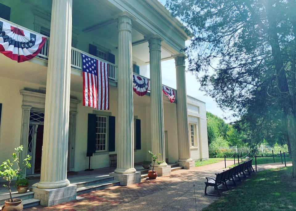 A white plantation-style house with grand columns, draped with patriotic bunting.