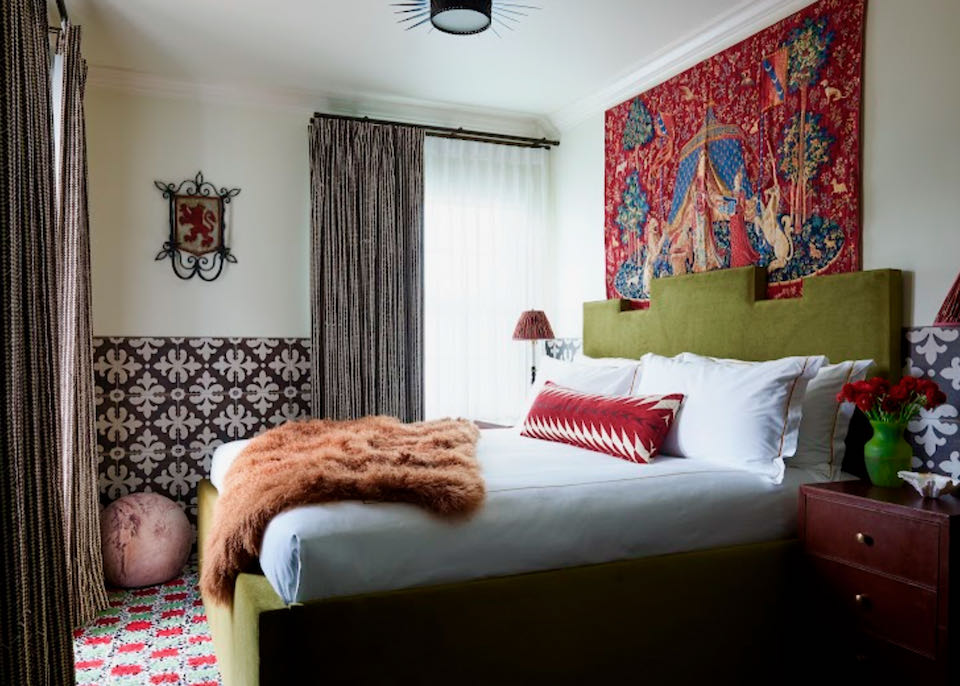 Sumptuous looking hotel room with colorful tapestry on the wall and custom tilework on the floor.