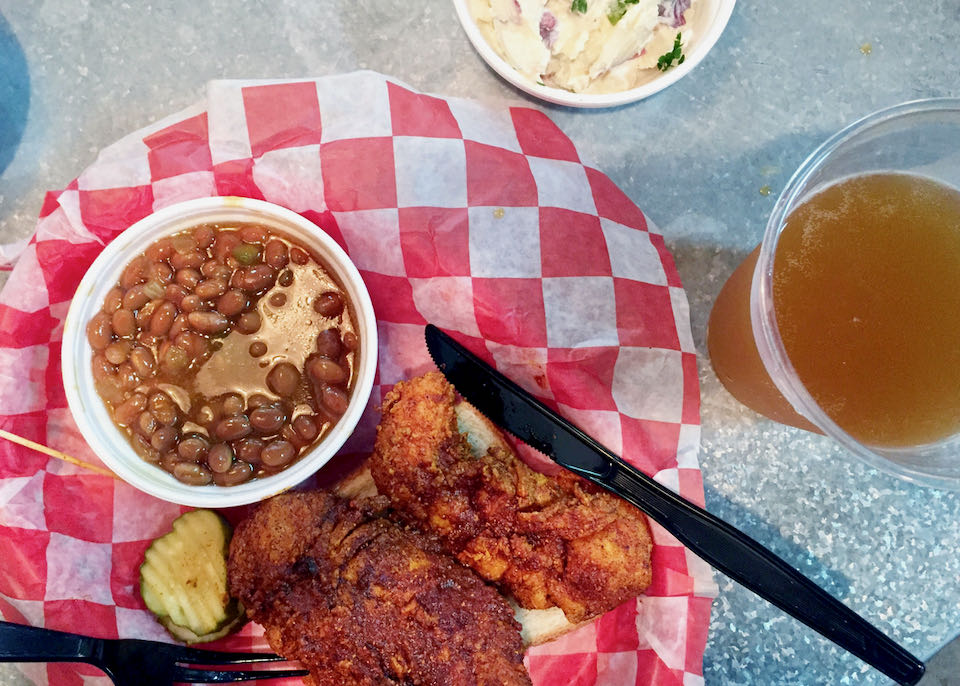 Overhead photo of spicy hot chicken with baked beans, potato salad and beer.