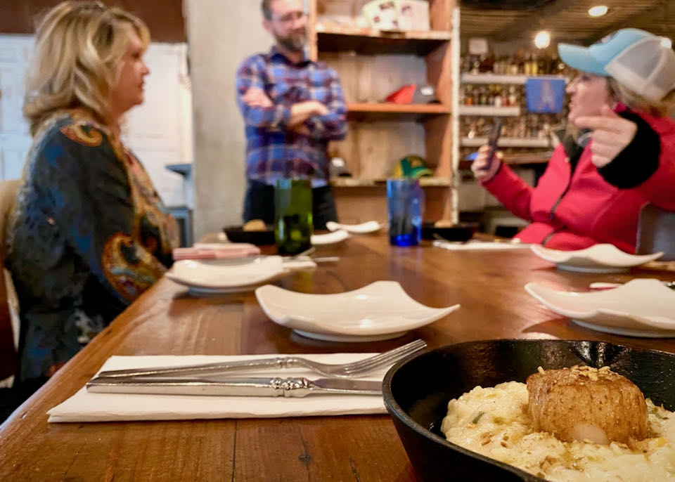 Barbecue and mashed potatoes in a cast iron skillet, with people talking in the background
