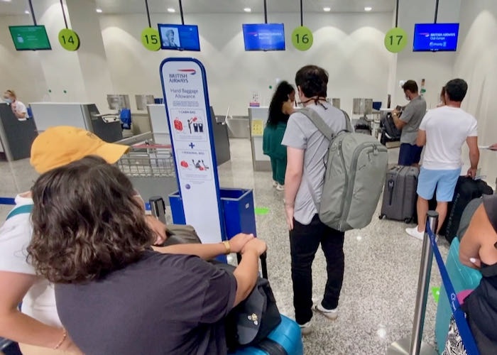 Travelers with luggage wait to check in at an airport.