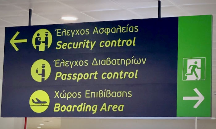 An airport sign pointing the way to security, passport control, and the boarding area.