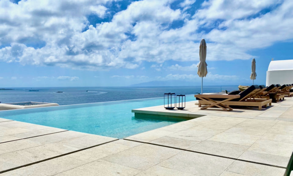 Wide flat paving stones around an infinity pool overlooking the blue sea.