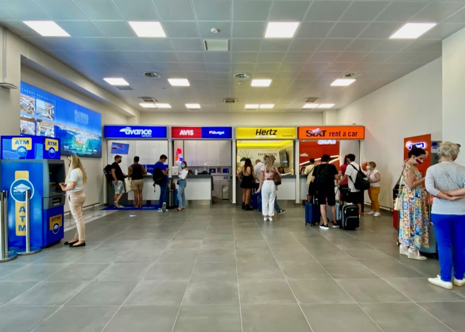 Avis, Hertz, and Sixt rental car kiosks at Mykonos airport.
