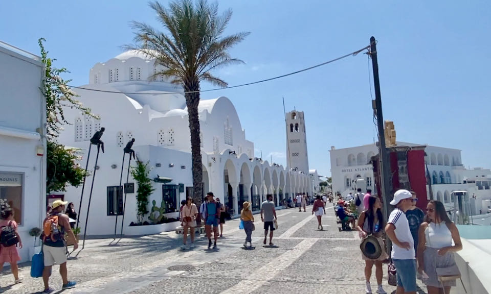A cobblestone pathway leading to a whitewashed Greek Orthodox Church. 