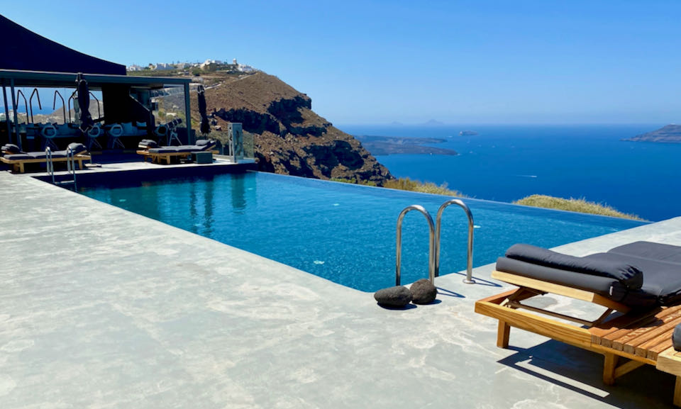 View of the Santorini Caldera and Aegean Sea from a concrete terrace with infinity pool