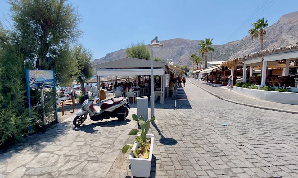 Stone paved road lined with restaurants, with a mountain in the background.