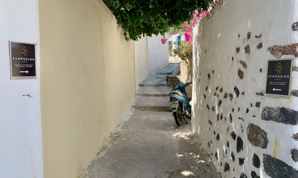 A set of long steps in a rustic alleyway, with a motorbike parked against the wall