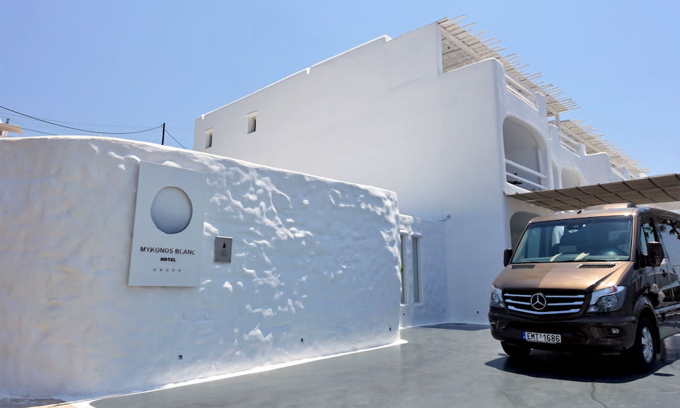 Smoothly-paved entrance to a white, boxy, island hotel.