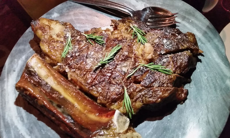 A medium-rare cooked steak on a plate, garnisged with rosemary