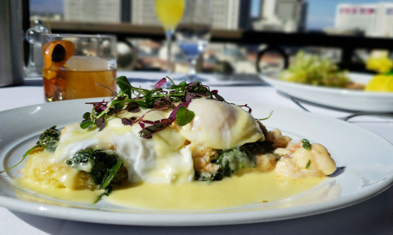 Two poached eggs atop greens and dressed with hollandaise sauce