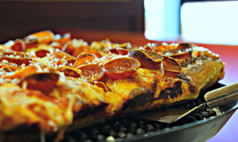 Close-up photo of a slice of pepperoni pan pizza with crispy edges