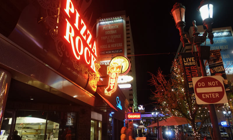 Neon lights of a pizza restaurant and other Downtown Las Vegas businesses at night