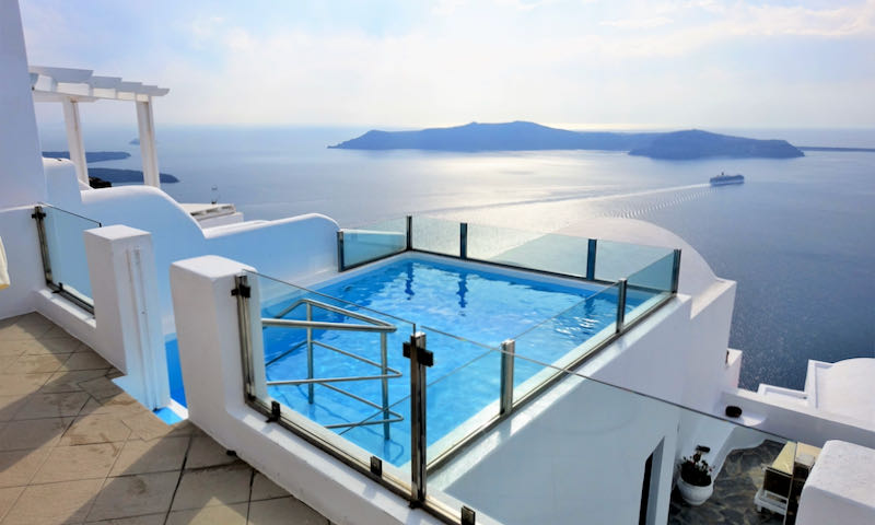 Small blue infinity pool overlooking the blue sea on a sunny day.