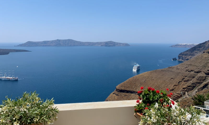 View over the Santorini Caldera from a sun deck with flowering plants