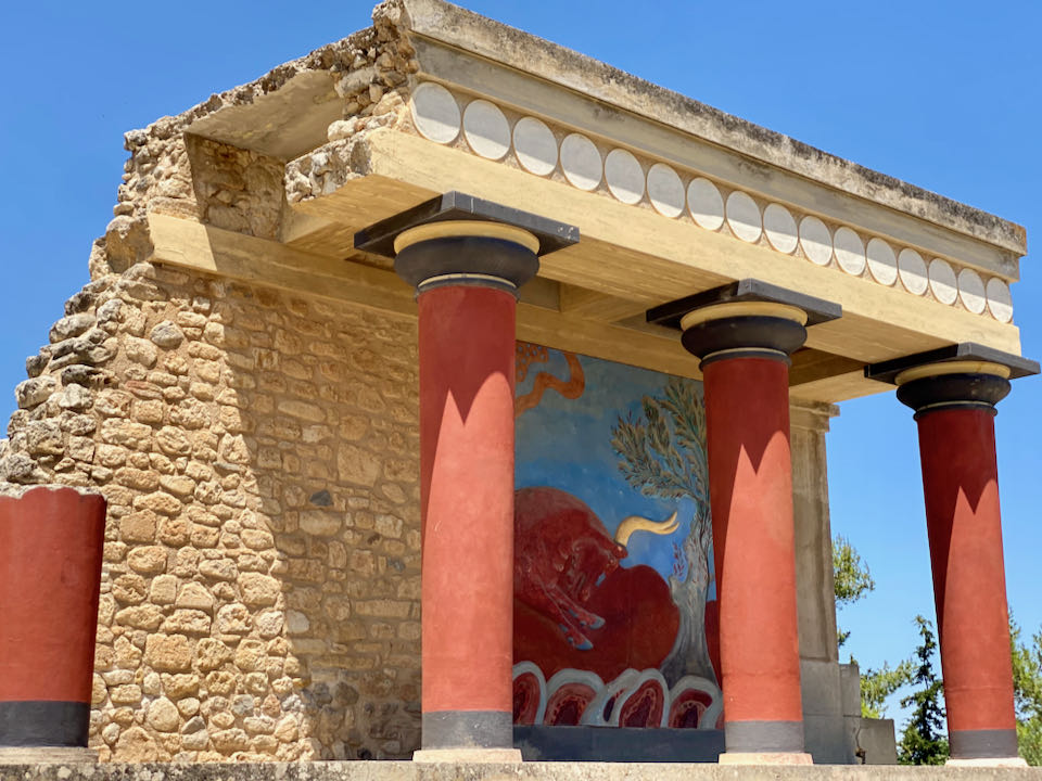 Ancient stone building with bright red pillars and a painting of a bull.