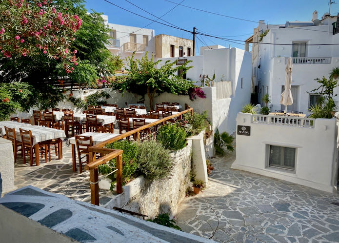 Tables set on a stone patio overlooking a pedestrian plaza 