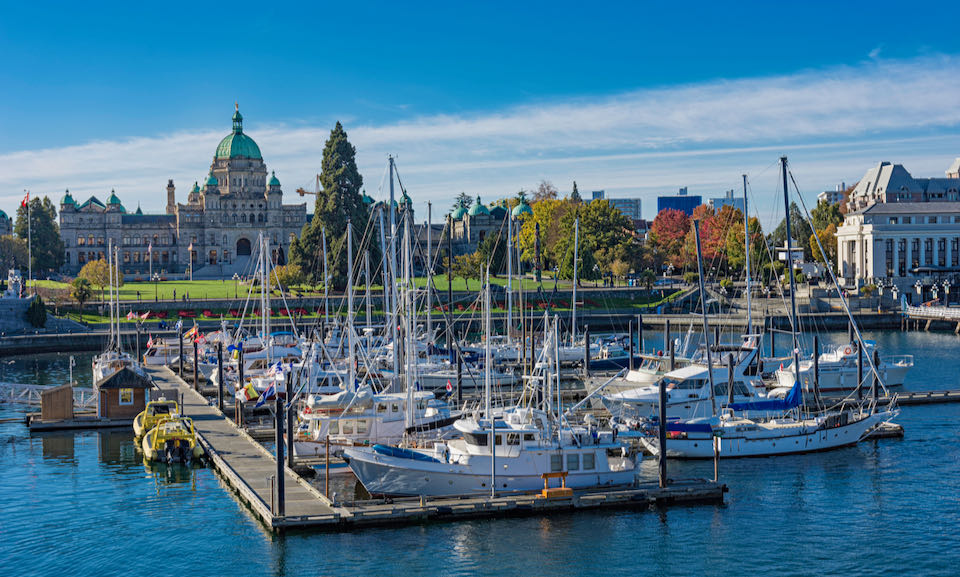 View of the British Columbia Parliament Building from Victoria Harbor, with boats in the foreground.